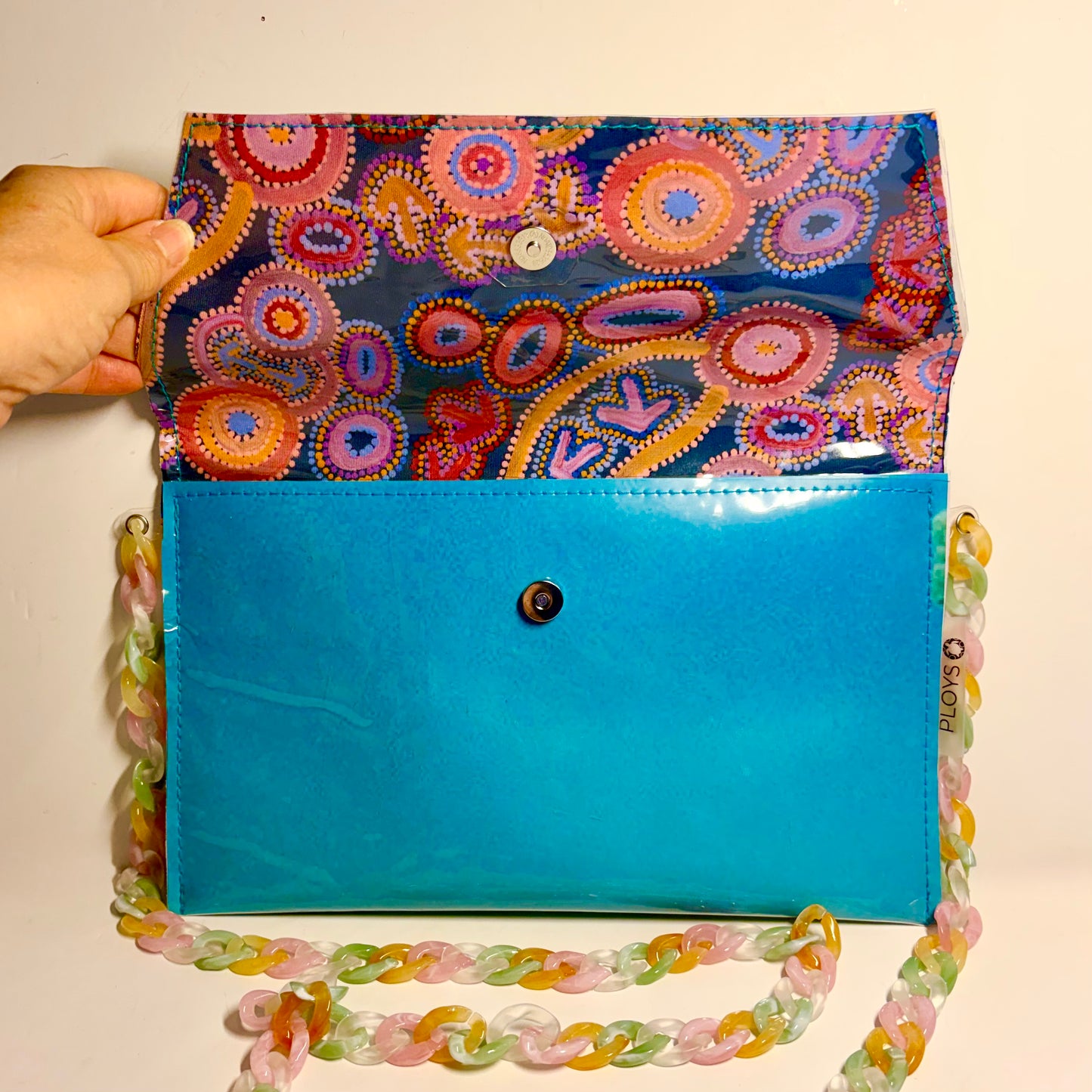 Colourful indigenous patterned clutch with a ocean themed blue base and decorative chain made from upcycled plastic 