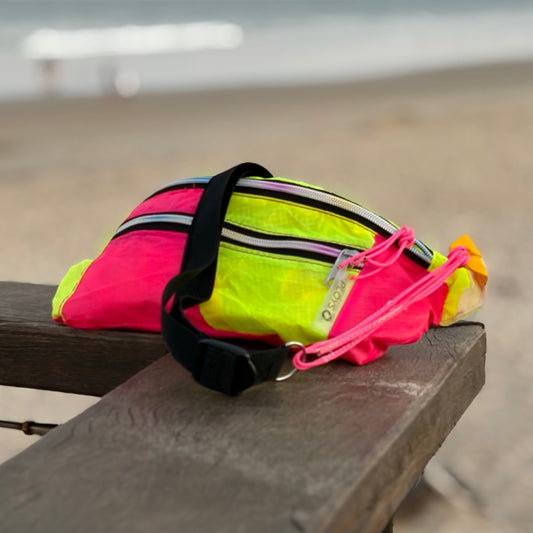 A bright neon pink and yellow reflective running waist bum bag with a black strap, made from upcycled paragliders