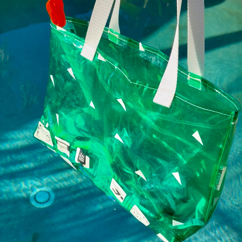A translucent green waterproof pool float beach swimming bag with white handles