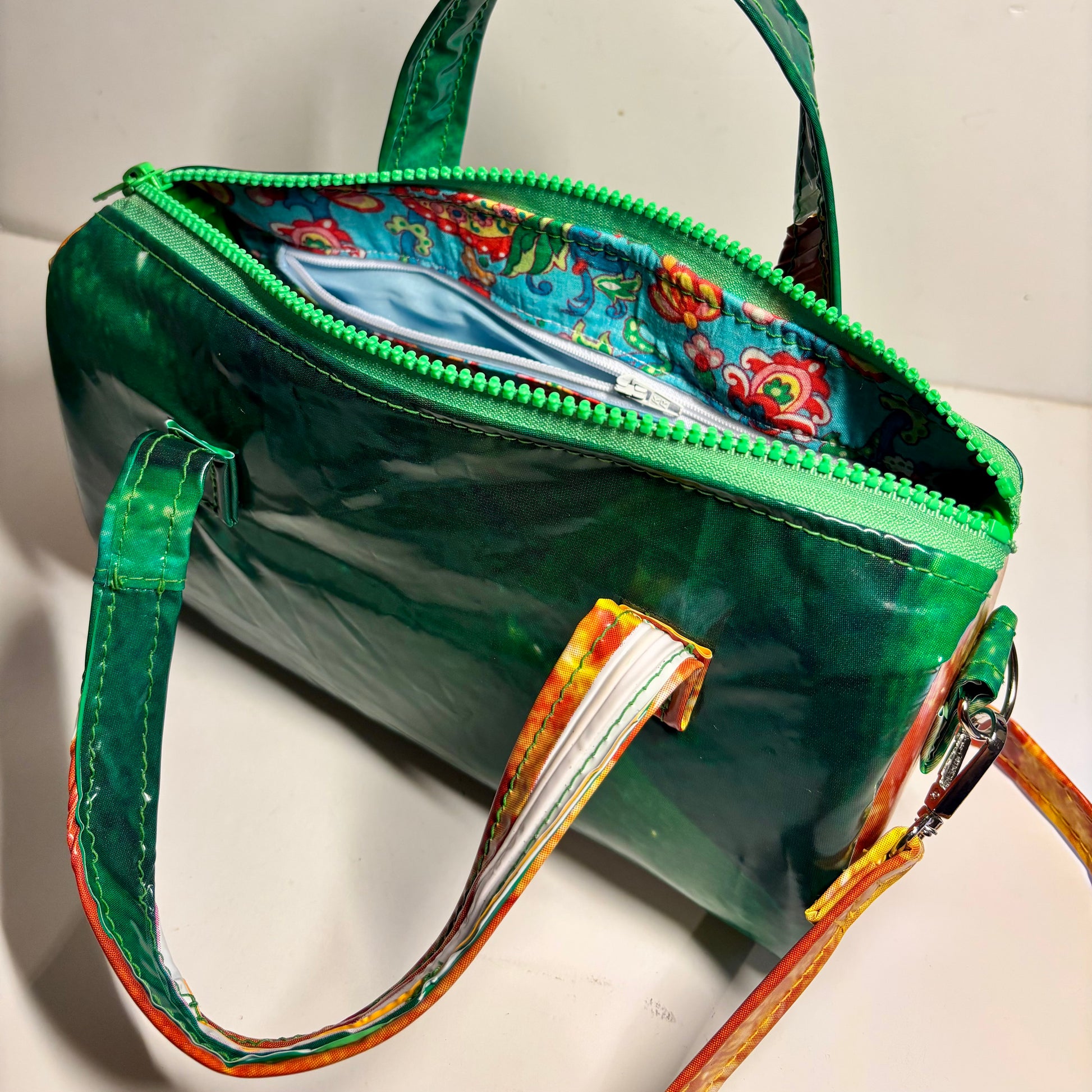 Dark green and orange oval shaped PVC handbag with strap in contrasting colours made from upcycled pool inflatables 