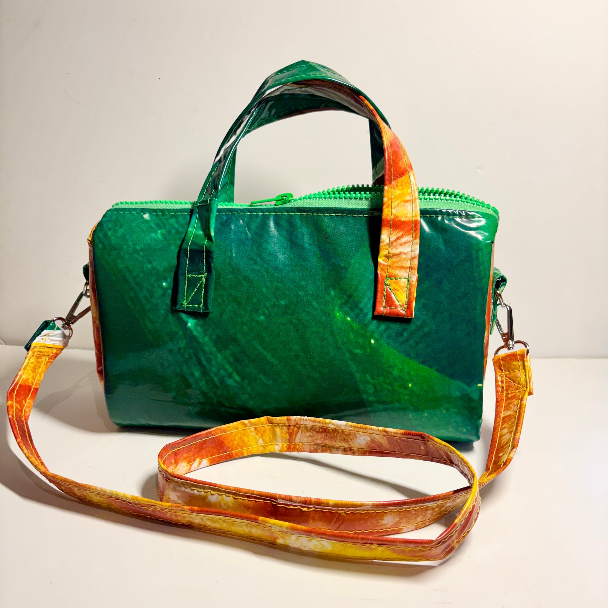 Dark green and orange oval shaped handbag with strap in contrasting colours made from upcycled pool inflatables 