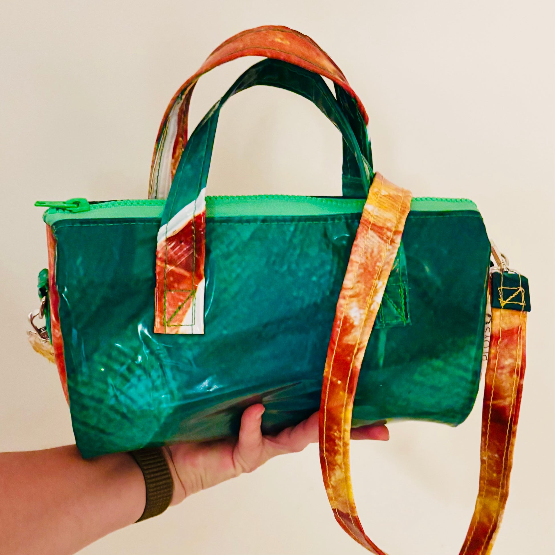 Dark green and orange oval shaped handbag with strap in contrasting colours made from upcycled pool inflatables 